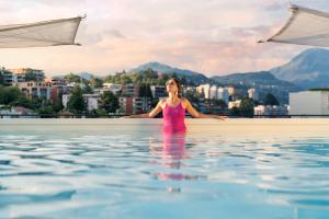 una mujer parada en el agua en una piscina en Hotel Admiral Lugano, en Lugano