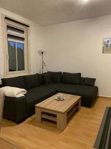 uma sala de estar com um sofá preto e uma mesa de centro em Ferienwohnung Eichhörnchen em Suhl