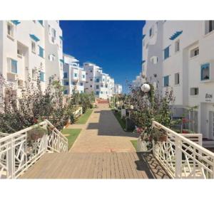 Smir Park appartement Haut standing Marina Smir في مارينا سمير: ممشى بين مبنيين طويلين عليه زهور