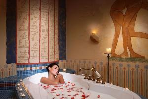 a woman laying in a bath tub with rose petals at Papuga Park Hotel Wellness Marrakesz & SPA in Bielsko-Biala