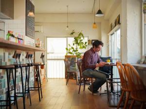 un hombre sentado en una mesa con un portátil en ROUTE - Cafe and Petit Hostel, en Nagasaki