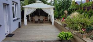 a wooden walkway with a white canopy in a garden at Apartament KAOLA in Jelenia Góra