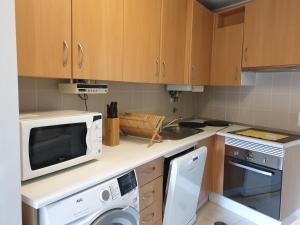 una pequeña cocina con microondas y lavavajillas en Altavista Penthouse T2, en Covilhã