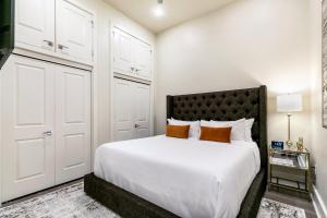 a bedroom with a bed with white sheets and orange pillows at The Calliope in New Orleans