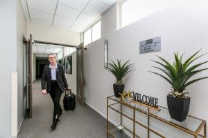 une femme qui marche dans un couloir dans un bureau avec des plantes dans l'établissement Quest New Plymouth Serviced Apartments, à New Plymouth