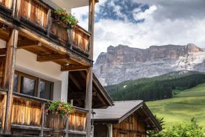 a building with flowers on the balconies with mountains in the background at Ciasa Agreiter in La Villa