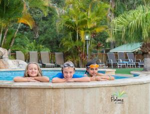 drei Kinder, die in einem Pool in einem Resort liegen in der Unterkunft The Palms At Avoca in Avoca Beach