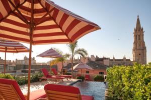 une terrasse avec des chaises, des parasols et une tour d'horloge. dans l'établissement Hotel Cappuccino - Palma, à Palma de Majorque