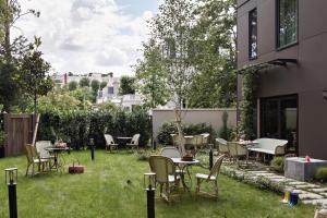 eine Terrasse mit Stühlen und Tischen auf dem Rasen in der Unterkunft Hôtel Botaniste in Paris