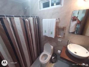 a man taking a picture of a bathroom with a toilet and sink at Hotel & Suites Mo Sak in Tapachula