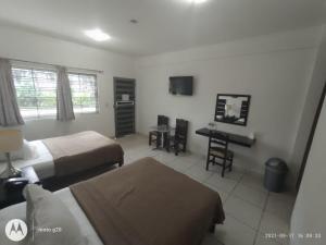 a hotel room with two beds and a desk at Hotel & Suites Mo Sak in Tapachula