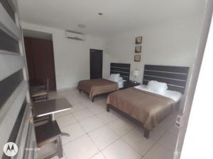 a hotel room with two beds and a table at Hotel & Suites Mo Sak in Tapachula