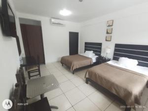 a hotel room with two beds and a chair at Hotel & Suites Mo Sak in Tapachula