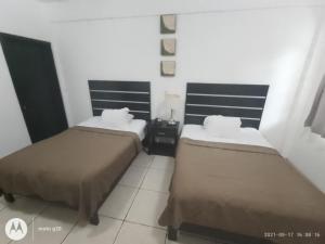 a hotel room with two beds and a tiled floor at Hotel & Suites Mo Sak in Tapachula