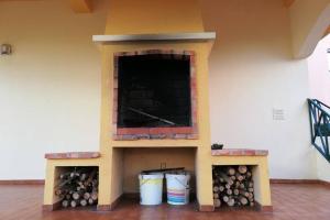 a fireplace with logs and buckets in a room at Beach House Villa At Peniche - Praia Consolação in Atouguia da Baleia