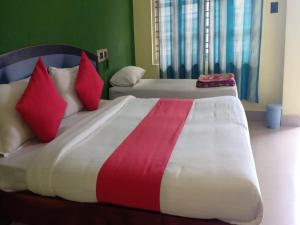 a bedroom with two beds with red and white pillows at Ice Berg Deluxe Lodge in Kushālnagar