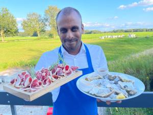 un homme tenant un plateau de nourriture sur une table dans l'établissement Villa BlauwHemel Diever, à Diever