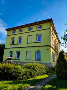 uma grande casa amarela com janelas brancas num quintal em Olsinky em Ústí nad Labem