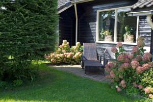 un patio con 2 sillas, una ventana y flores en Het Jachthuus - Vakantiewoning Oscar Hoeve, en Ede