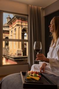 een vrouw in een hotelkamer met een glas wijn bij Windsor Hotel in Cordoba