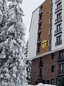 uma árvore coberta de neve em frente a um edifício em Jahorinska Vila em Jahorina