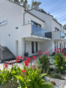 una casa blanca con flores rojas en el patio en Apartamenty Marco Polo, en Dziwnówek