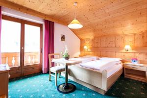 a bedroom with a bed and a table in a room at Gasthof Tuscherhof in Braies