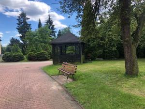 een parkbankje naast een tuinhuisje in een park bij Hotel Zameczek in Radomsko