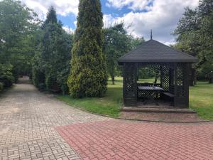 een tuinhuisje met een bank in een park bij Hotel Zameczek in Radomsko