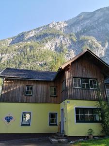 une maison en bois avec une montagne en arrière-plan dans l'établissement Haus Waldbach, à Hallstatt