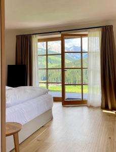 een slaapkamer met een bed en een groot raam bij Surrounded by green - Luxury Chalet at the foot of the Dolomites in La Villa