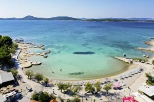 Infinity Appartements in Vodice - Nord-Dalmatien في فوديس: شاطئ فيه مظلات وناس في الماء