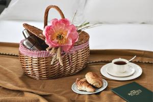 einen Tisch mit einem Korb, einer Tasse Kaffee und Croissants in der Unterkunft Hôtel Botaniste in Paris