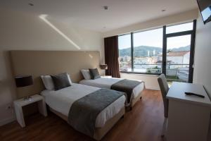 a hotel room with two beds and a desk at Hotel Quinta do Viso in Miranda do Corvo