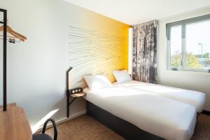 ボワ・ダルシーにあるB&B HOTEL Bois d'Arcy Saint Quentin en Yvelinesのベッド2台と窓が備わるホテルルームです。