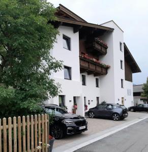 ein weißes Gebäude mit davor geparkt in der Unterkunft Appartementhaus Hüttenberger in Erpfendorf