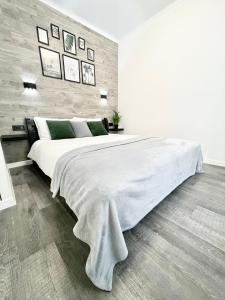 1 dormitorio blanco con 1 cama blanca grande con almohadas verdes en Элегантная квартира-студия ЖК Рич Таун, Ирпень, en Irpín