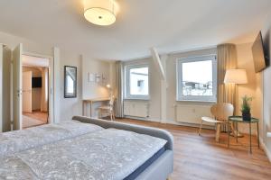 a bedroom with a bed and a desk and two windows at Apartmenthaus Tribseer Damm 6 in Stralsund