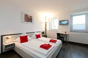 a bedroom with a bed with red pillows on it at Hotel zwischen den Seen in Waren