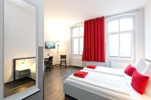 a bedroom with two beds with red pillows and a desk at Hotel zwischen den Seen in Waren