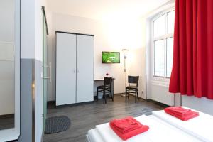 a room with two beds and a desk with a red curtain at Hotel zwischen den Seen in Waren