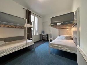 two bunk beds in a room with a desk at Le Coffice Auberge de Jeunesse in Paris