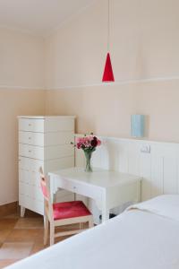 a bedroom with a white desk with a vase of flowers at Marin Hotel in Pula