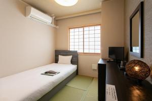 een kleine kamer met een bed en een televisie bij Bakery Hotel Chateau D'or in Nara