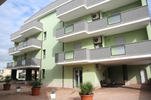 uma vista exterior de um edifício verde com vasos de plantas em Isa Residence Fiumicino Airport em Fiumicino