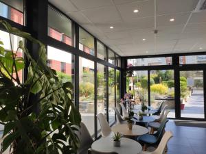 a restaurant with tables and chairs and a plant at Novotel Suites Paris Montreuil Vincennes in Paris