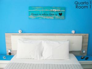 een slaapkamer met een bed met een blauwe muur bij Alojamento Tiago & Jorge Guesthouse in Nazaré