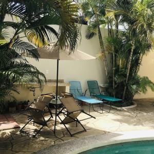 a group of chairs and an umbrella next to a pool at Bed and Breakfast Pecarí in Cancún