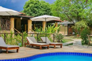 eine Terrasse mit Stühlen und Sonnenschirmen neben einem Pool in der Unterkunft Pousada Flores do Cerrado in Pirenópolis