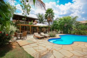 einen Hinterhof mit einem Pool und einer Terrasse mit einem Tisch und Stühlen in der Unterkunft Pousada Flores do Cerrado in Pirenópolis